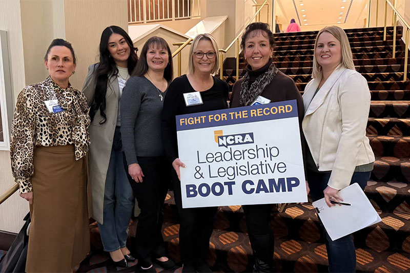 NCRA Boot Camp group of attendees holding sign near stairs