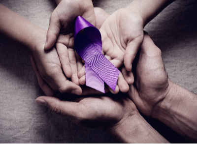 Hands holding a purple ribbon for Domestic Violence Awareness Month